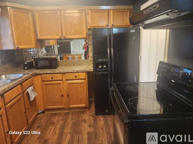 A kitchen with wooden cabinets and a black refrigerator.