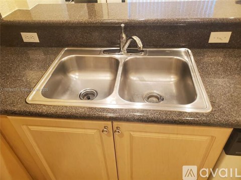 A double sink in a kitchen with a granite counter top.