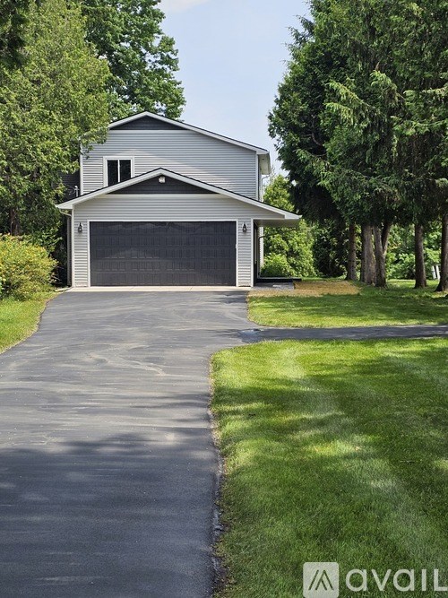A two-car garage is situated on a tree-lined street.