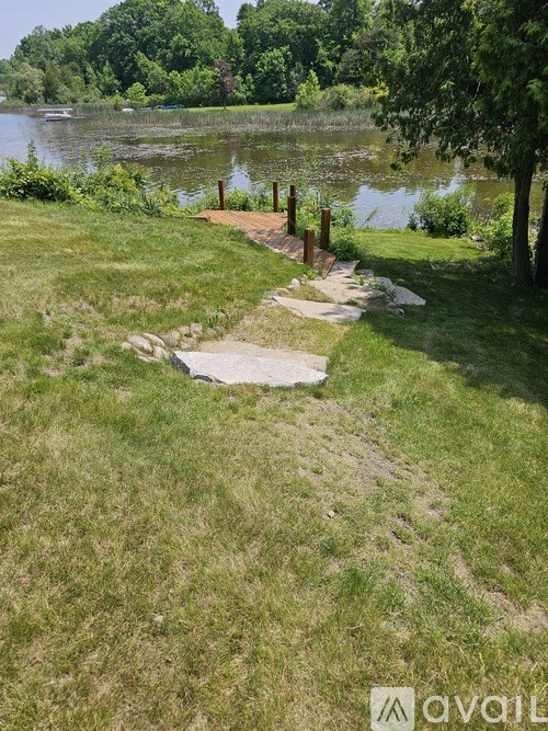 A grassy area with a wooden walkway leading to a body of water.