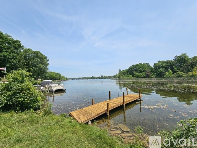 A wooden dock extends into a calm lake surrounded by lush greenery.