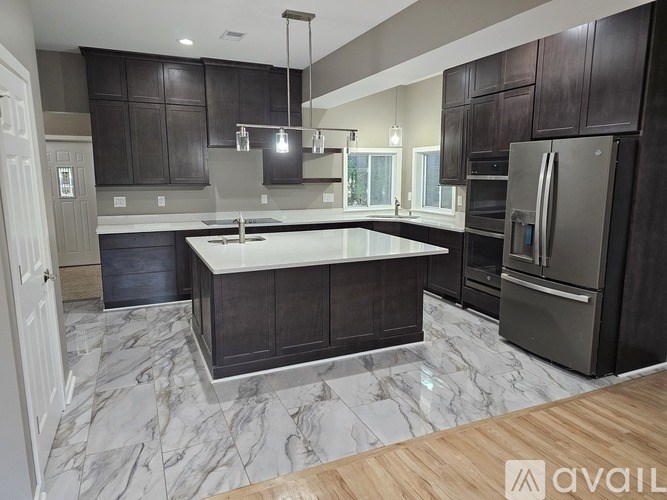 A kitchen with dark brown cabinets and a marble floor.