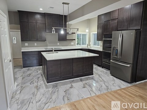 A kitchen with dark brown cabinets and a marble floor.