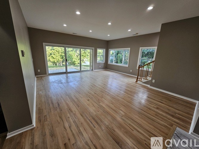 A spacious room with wooden flooring and large windows.