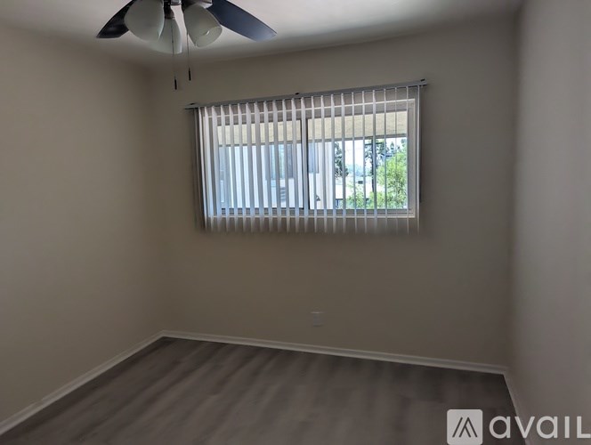 A room with a ceiling fan and a window with blinds.
