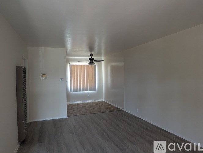 A room with a ceiling fan and a window with blinds.