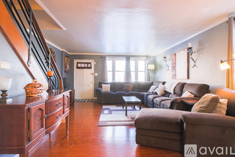 A living room with a brown couch and a wooden floor.