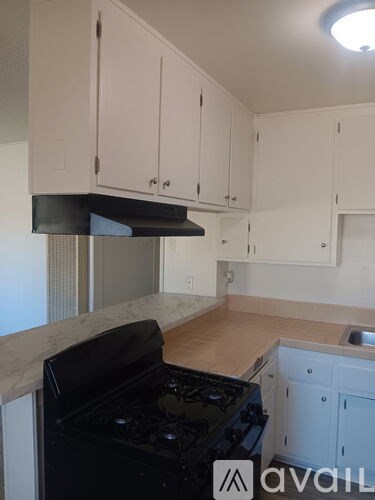 A kitchen with white cabinets and a black stove top.