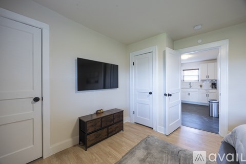 A living room with a flat screen TV mounted on the wall and a wooden coffee table in the center.