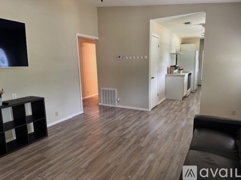 A living room with a black couch and a television on the wall.