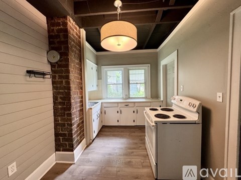 A kitchen with a brick column and a white stove top oven.