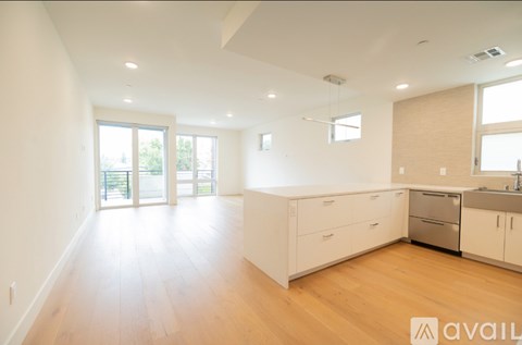 A spacious kitchen with white cabinets and a wooden floor.