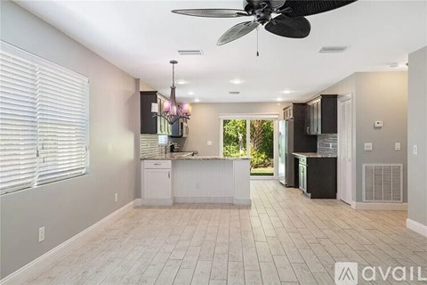 A spacious kitchen with a fan and a window with blinds.