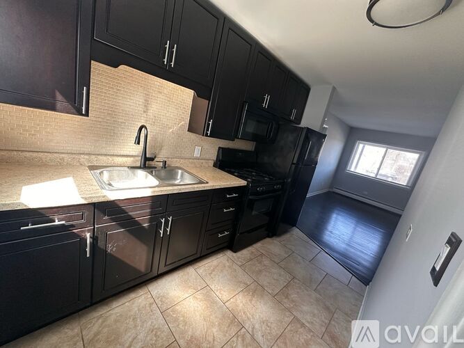 A kitchen with black cabinets and a tiled floor.