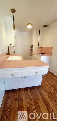 A kitchen with a sink and wooden floors.
