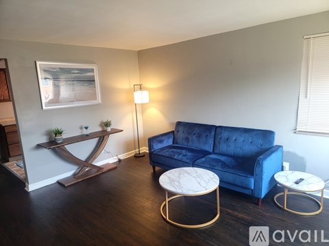 A living room with a blue couch, a wooden floor, and a painting on the wall.