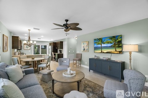 A living room with a grey couch, a coffee table, and a painting of a beach scene on the wall.