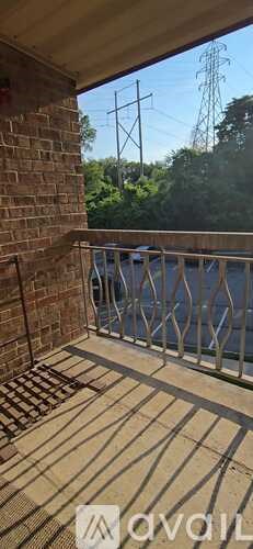 A balcony with a metal railing and a brick wall.