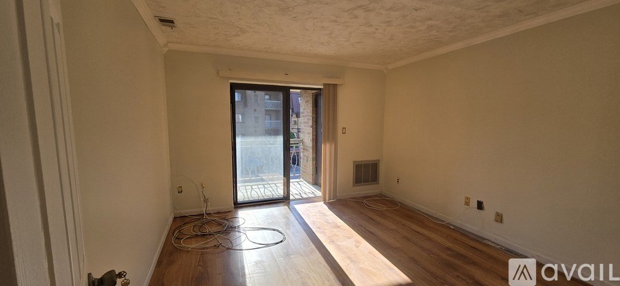 A room with wooden floors and a sliding glass door leading to a balcony.