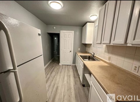 A kitchen with white cabinets and a white fridge.