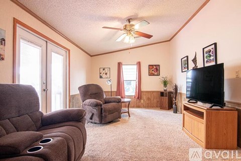 A living room with a grey couch, a brown chair, and a television on a wooden stand.