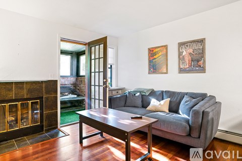 A living room with a grey couch and a fireplace.