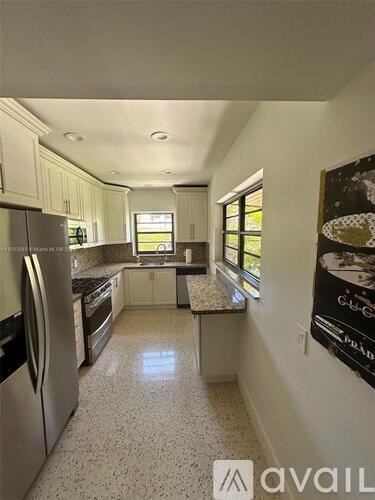 A kitchen with white cabinets and a granite countertop.