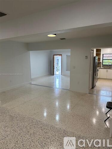 A spacious room with a marble floor and a doorway leading to another room.