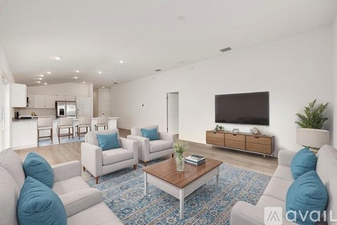 A living room with white furniture and a blue rug.