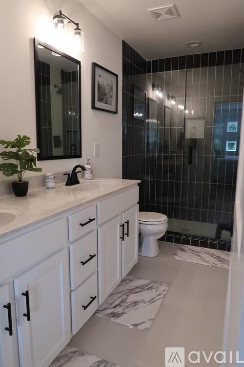 A bathroom with a white counter top and a black and white tiled shower.