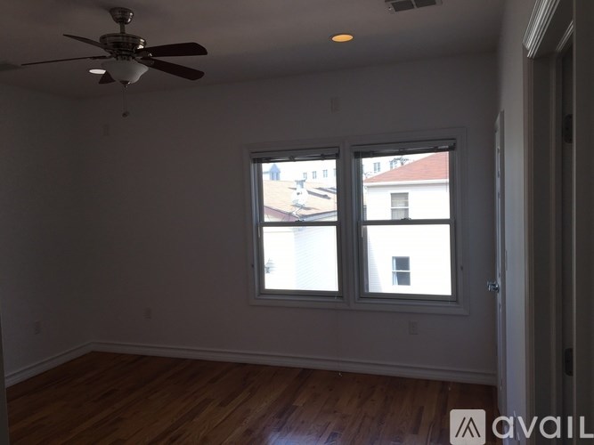 A room with a ceiling fan and two windows.