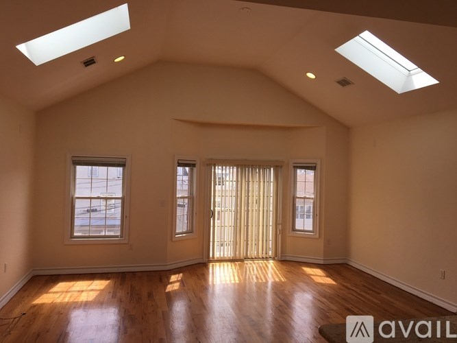 A spacious room with wooden floors and skylights.