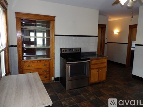A kitchen with a black stove top oven and a wooden cabinet.