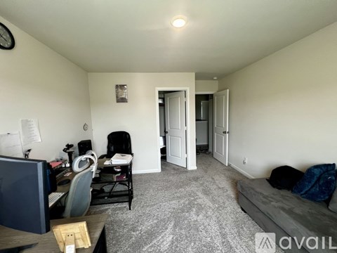 A living room with a grey couch and a desk with a computer.