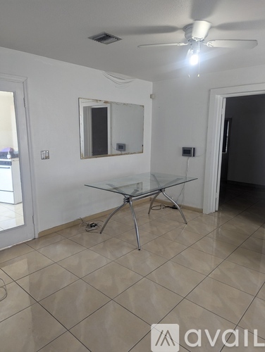 A room with a glass table and a ceiling fan.