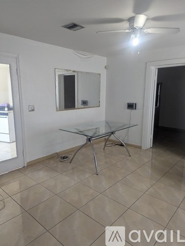 A room with a glass table and a ceiling fan.