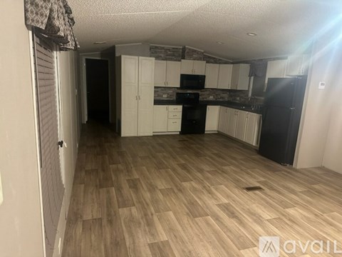 A kitchen with wooden flooring and white cabinets.