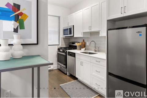 A kitchen with white cabinets and a stainless steel refrigerator.