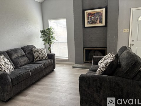 A living room with a grey couch and a fireplace.