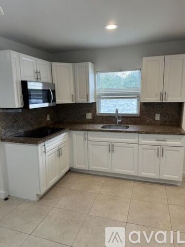 A kitchen with white cabinets and a granite countertop.