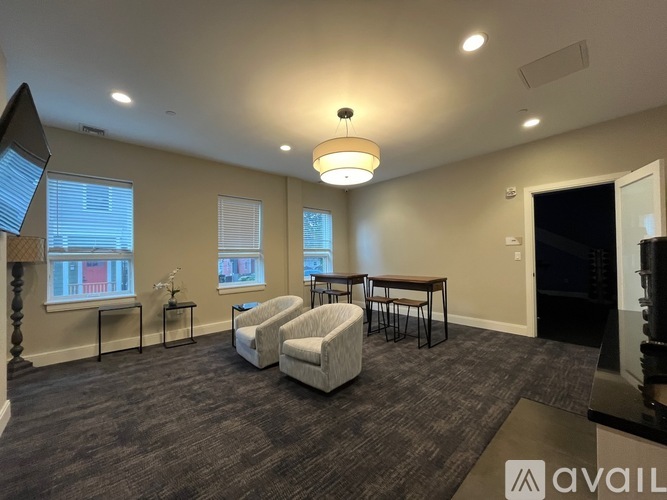 A living room with a grey carpet and a white sofa.