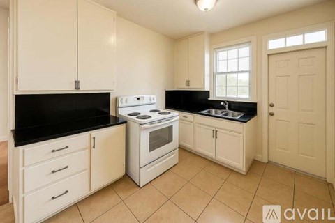 A kitchen with white cabinets and black countertops.