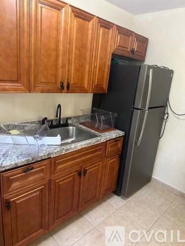 A kitchen with wooden cabinets and a black fridge.