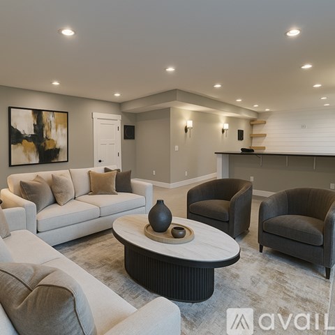A modern living room with a white sofa, grey armchairs, and a coffee table with a vase on it.