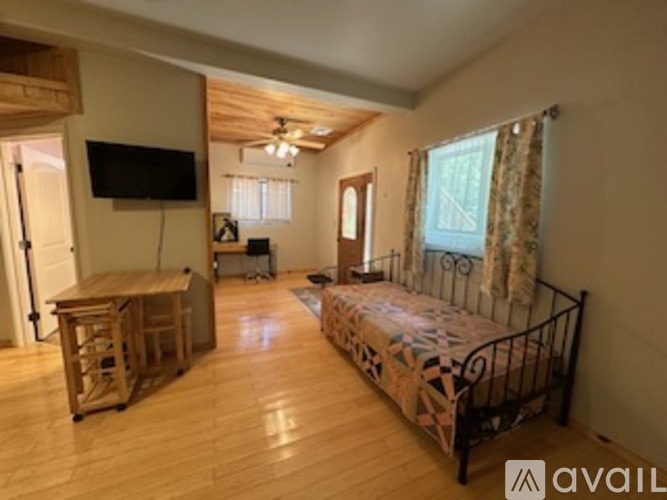 A bedroom with a bed, a television, and a window with curtains.