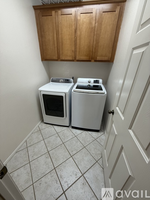 A white microwave and oven are sitting on a tiled floor in a kitchen.