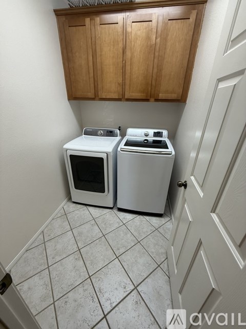 A white microwave and oven are sitting on a tiled floor in a kitchen.