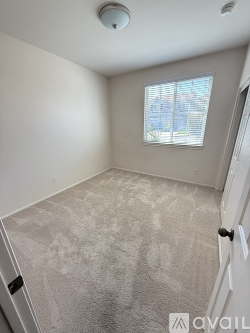 A room with a carpeted floor and a window with blinds.