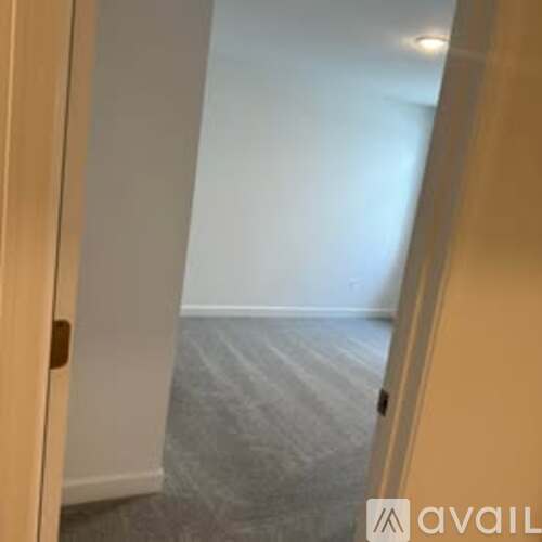 A hallway with a carpeted floor and white walls.