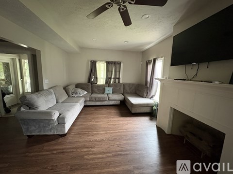 A living room with a grey couch and a television on the wall.